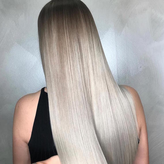 Back of woman’s head with long, straight, gray blonde ombre hair, created using Wella Professionals.