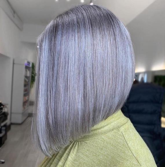 Side profile of woman with blunt, violet-grey bob haircut.