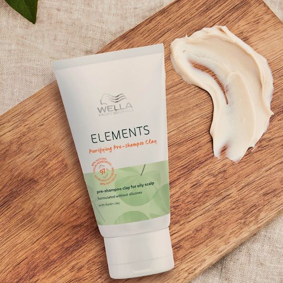 A bottle of Elements Pre-Shampoo Clay Mask by Wella Professionals on a wooden board