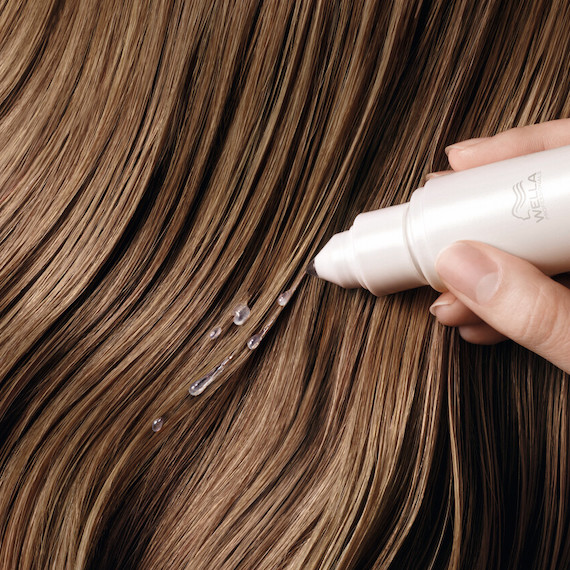 Close-up of Wella Professionals Fusion Amino Refiller being applied to hair.
