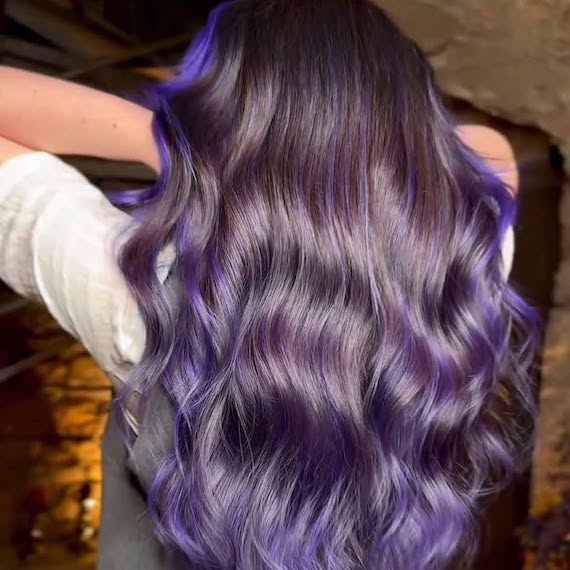 Back of model’s head with long, wavy, dark hair and amethyst highlights.