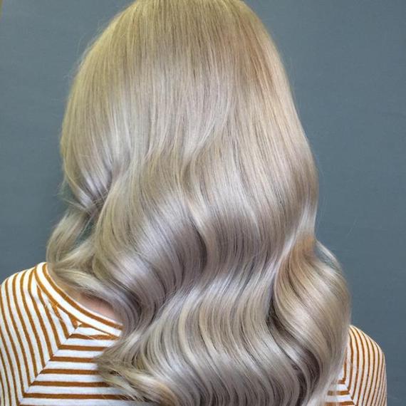 Photo of the back of a woman’s head with long, wavy, blonde hair, glossed using Wella Professionals