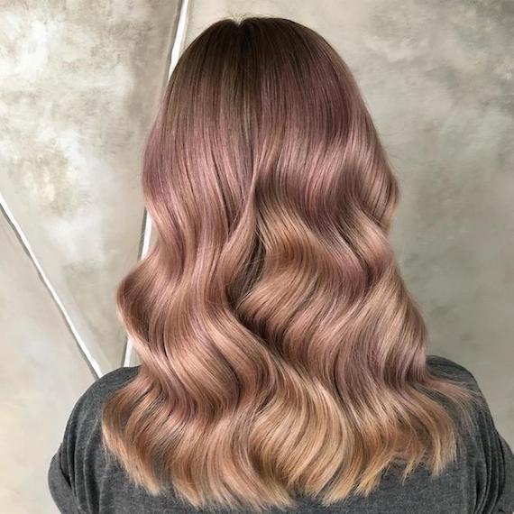 Photo of the back of a woman’s head with shiny, tousled, rose gold hair, glossed using Wella Professionals