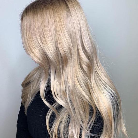 Side profile of woman with long, wavy, blonde hair, glossed using Wella Professionals