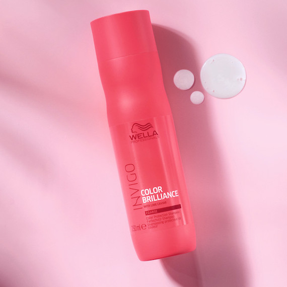 Bottle of Wella Color Brilliance Shampoo on a pink background.
