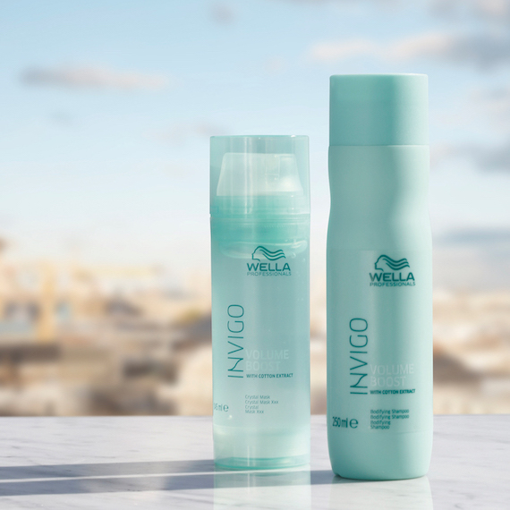 Bottles of Wella Volume Boost Shampoo and Crystal Mask set against a blue sky backdrop.