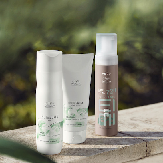 Bottles of Wella NutriCurls Shampoo, Conditioner and Fresh Up Spray set against a leafy green backdrop.