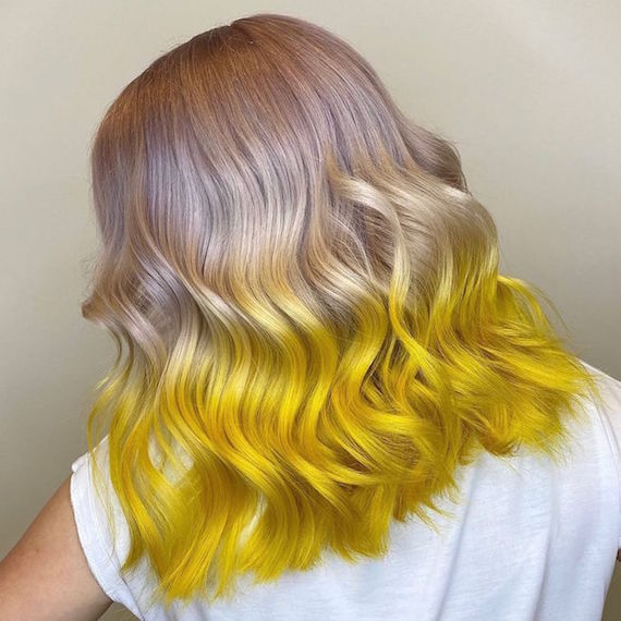 Back of woman’s head with half and half hair color in violet blonde and neon yellow, created using Wella Professionals.