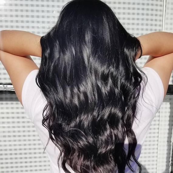 Back of woman’s head with long, shiny, black, wavy hair, created using Wella Professionals.