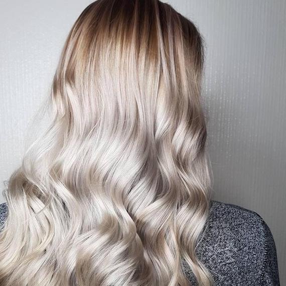 Back of a woman’s head showing long, wavy, ice blonde hair, created using Wella Professionals.