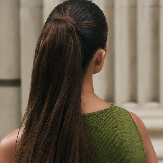 Back of model’s head with long, brown hair tied in a ponytail.