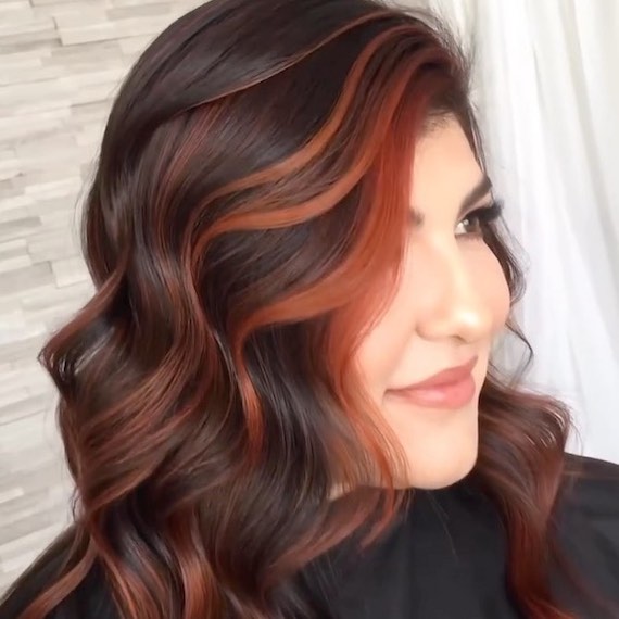 Side profile of a person a red and black high contrast balayage hairstyle
