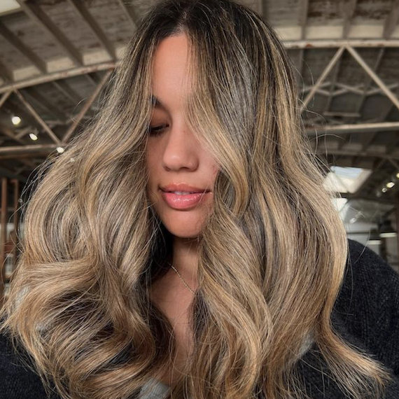 Head of a person with high contrast caramel balayage hair looking down