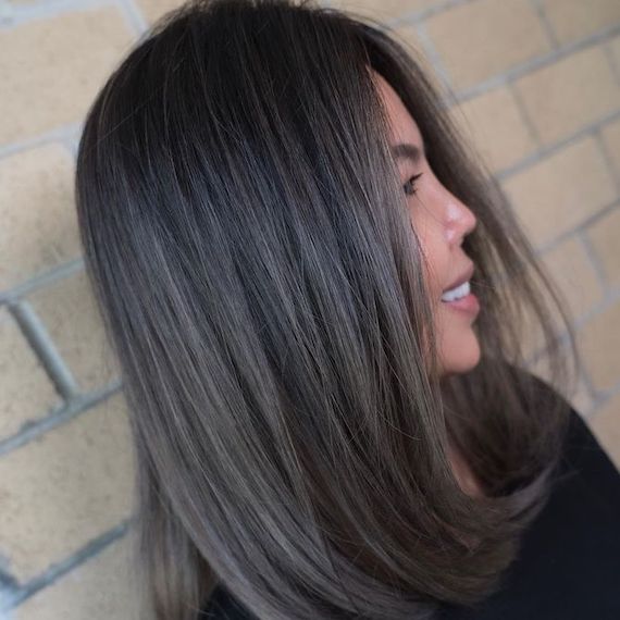 Side profile of model with should-length, black hair and silver gray ombre highlights.