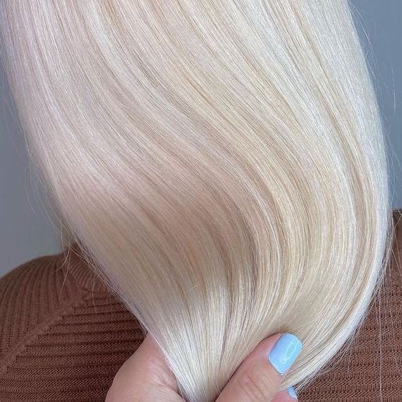 Close up of straight hair that’s been coloured all over in vanilla blonde, from golden blonde highlights.