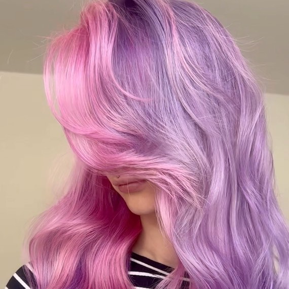 Model with long, wavy, purple hair featuring hot pink through the face frame.