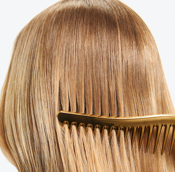 Close-up of model’s golden blonde hair being combed with a wide-tooth comb.