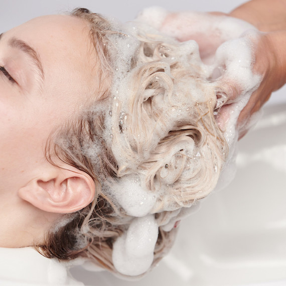 Close-up of model having their long, blonde hair washed in a salon sink.
