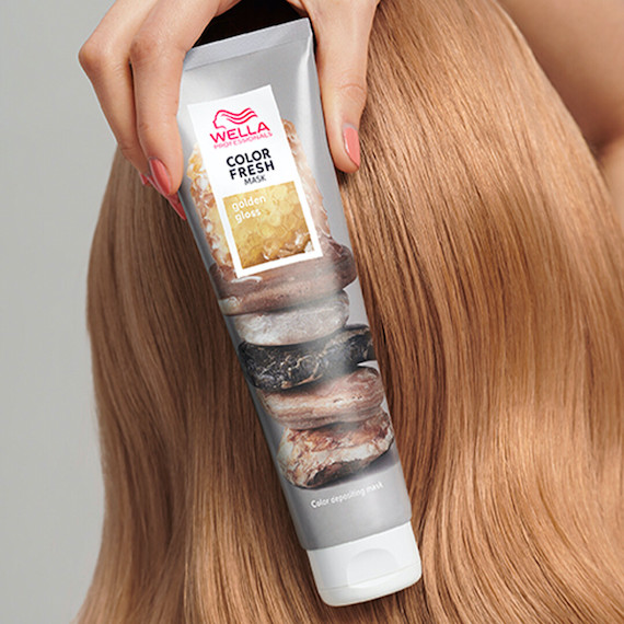 Model with golden blonde hair holds up a tube of the Color Fresh Mask in Golden Gloss.