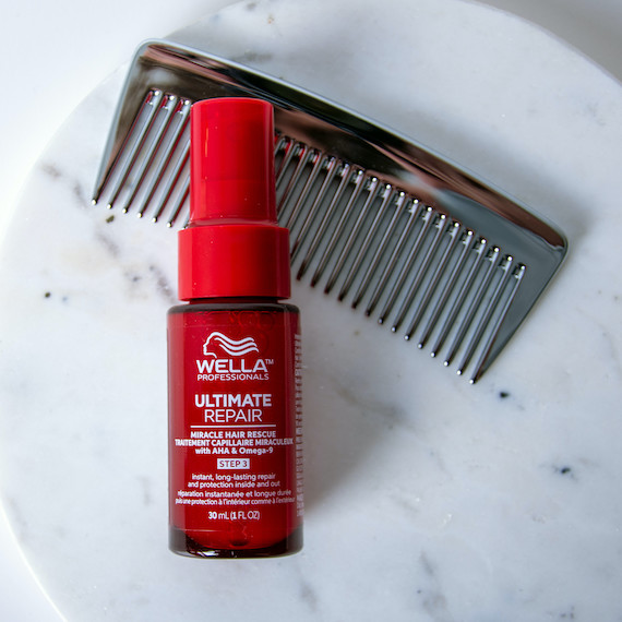 Ultimate Repair Miracle Hair Rescue and a wide tooth comb on a marble surface.