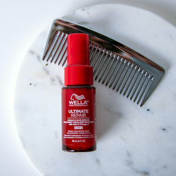 A comb and a bottle of Ultimate Repair Miracle Hair Rescue on a marble surface.