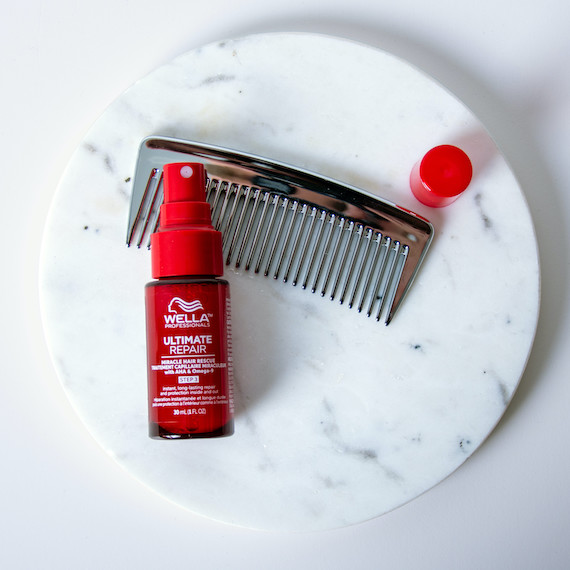 ULTIMATE REPAIR Miracle Hair Rescue on a marble surface next to a comb.