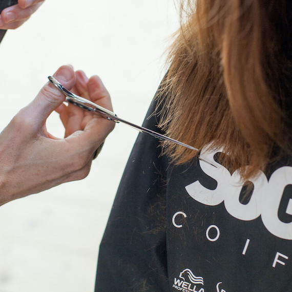 Close-up of dark brown hair being trimmed by a stylist.