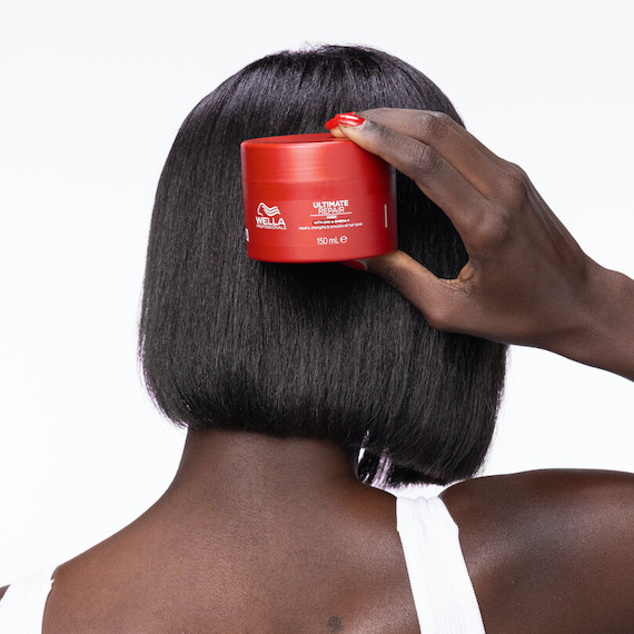 Model with dark brown bob haircut holds up ULTIMATE REPAIR Mask.
