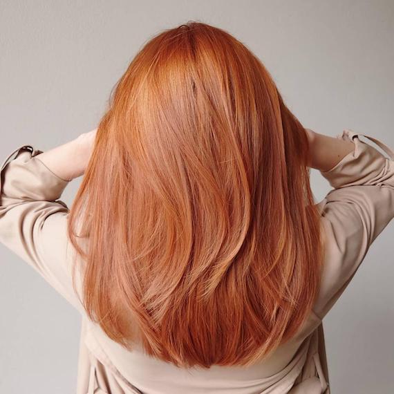 Back of woman’s head with straight, mid-length, copper hair, created using Wella Professionals.