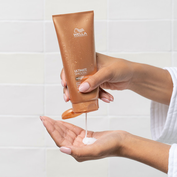 Model squeeze ULTIMATE SMOOTH Conditioner into hand.