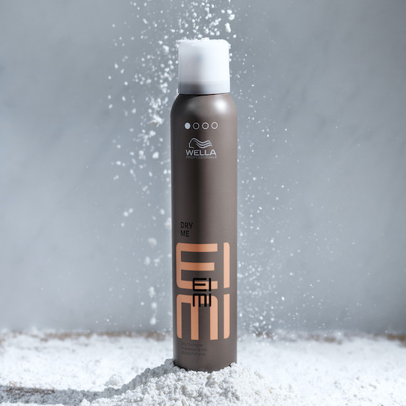 A can of EIMI Dry Me dry shampoo on a gray background.