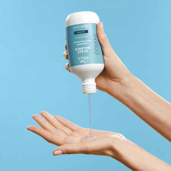 Model pours INVIGO Scalp Balance shampoo into palm of hand.