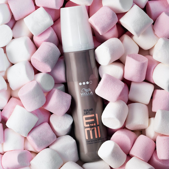 Bottle of EIMI Sugar Lift texture spray surrounded by marshmallows.