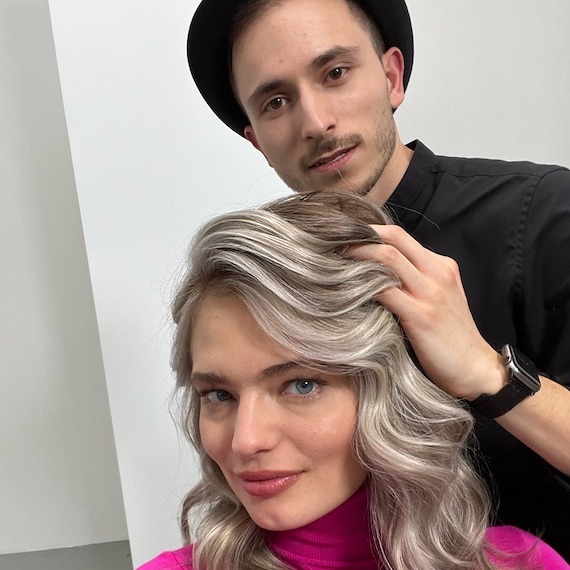 A hairdresser styles a model’s icy blonde hair.