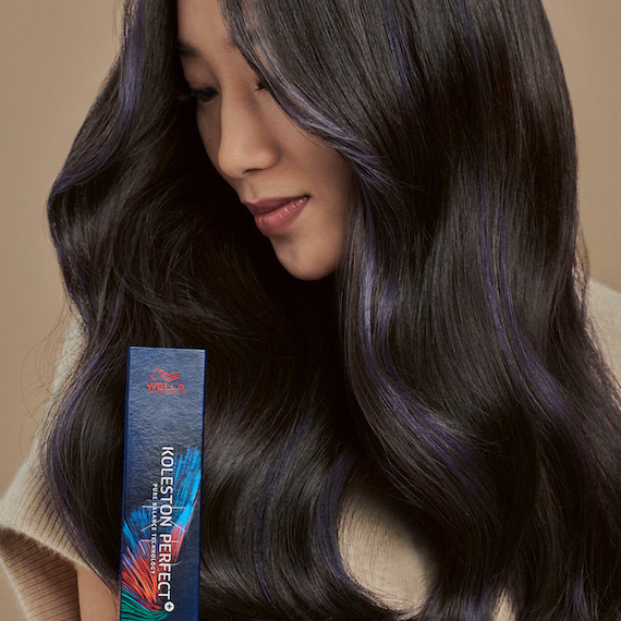 Side profile of model with dark hair colored using Koleston Perfect by Wella Professionals, which she holds in her hand