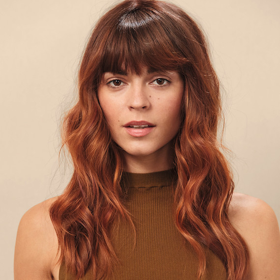 Woman faces camera with long, wavy, brown hair and auburn highlights created by Wella Professionals.