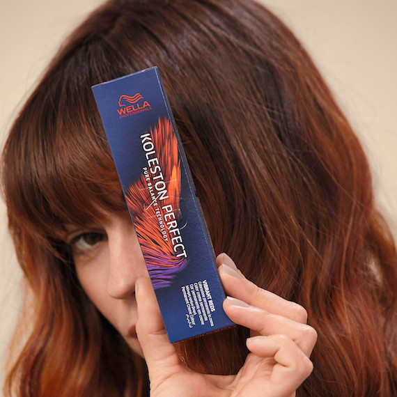 Close-up of auburn hair as woman holds Koleston Perfect color.