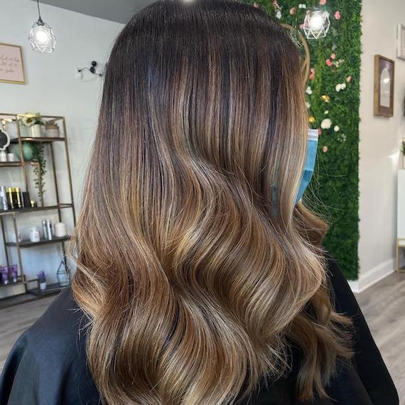 Back of woman’s head with brunette hair and caramel highlights, created using Wella Professionals. 