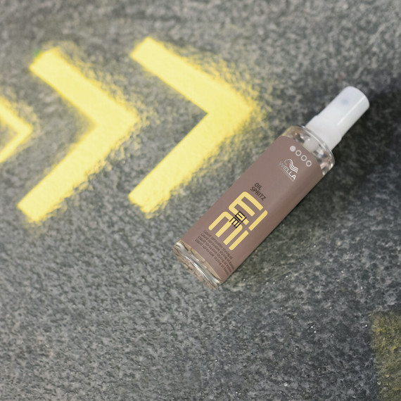 Bottle of EIMI Oil Spritz laying on the street. 