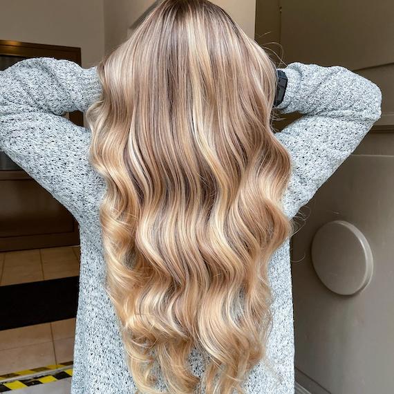 Back of woman’s head with long, wavy, beachy blonde hair.