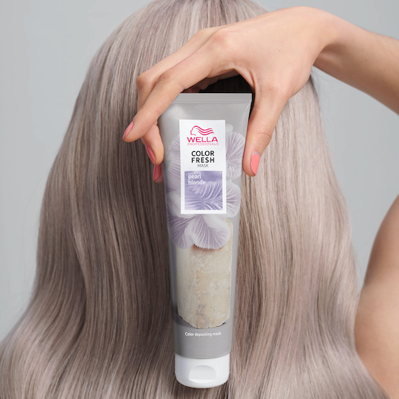Back of woman’s head with long blonde hair as she holds up the Color Fresh Mask in Pearl Blonde.