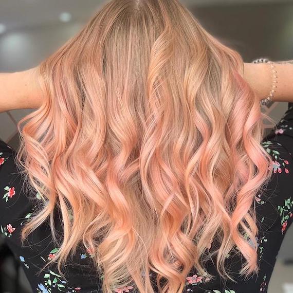 Back of woman’s head with long, loosely curled, peachy-pink hair, created using Wella Professionals.
