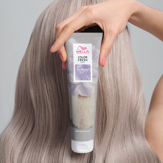 Model holds a tube of the Color Fresh Mask in Pearl Blonde in front of her long, blonde hair.