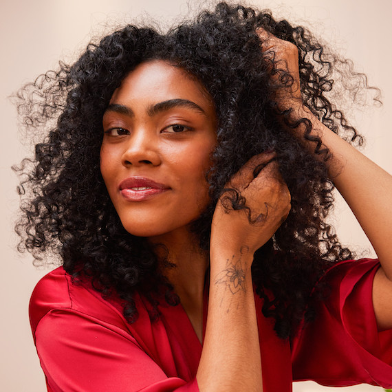 Model smooths hands through their dark, curly hair.