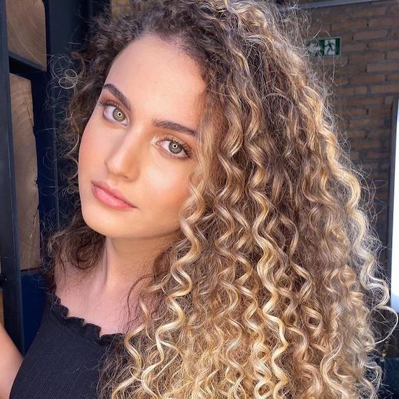 Woman smiling at the camera with long, curly, medium blonde hair.