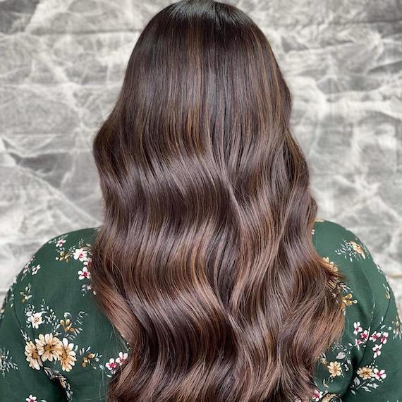 Back of woman’s head with long, wavy, medium mocha brown hair, created using Wella Professionals.