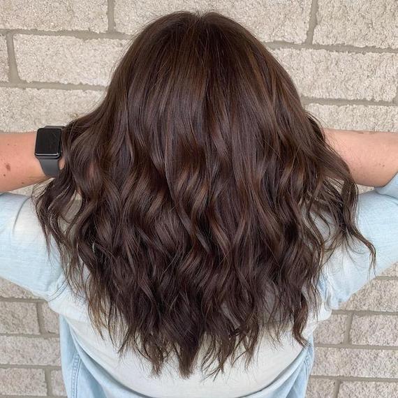 Back of woman’s head with tousled, dark mocha brown hair, created using Wella Professionals.