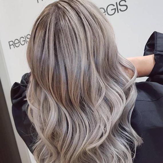 Back of woman’s head with long, wavy hair and mushroom blonde highlights, created using Wella Professionals.