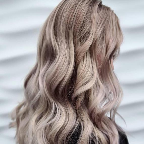 Side profile of woman with beachy mushroom blonde waves, created using Wella Professionals.