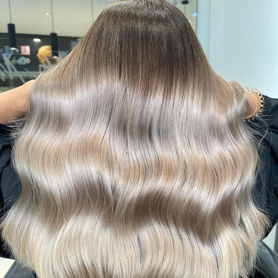 Back of woman’s head with long, wavy, silver mushroom blonde hair, created using Wella Professionals.